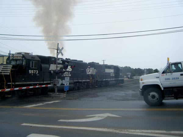 A Norfolk Southern Company train travels through the crossing at Ellis Road and Angier Avenue as a truck waits behind the four quadrant gates that are designed to keep motorists out of the way of moving trains.